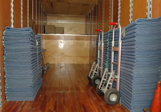 A room filled with many carts of blue towels.