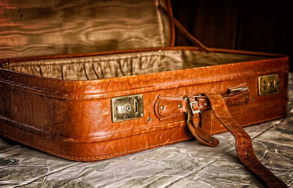 A brown suitcase sitting on top of a bed.