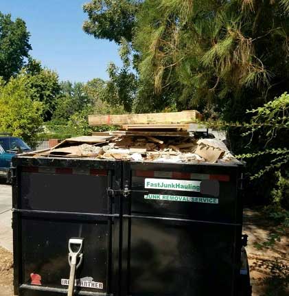 A dumpster full of wood and other debris.