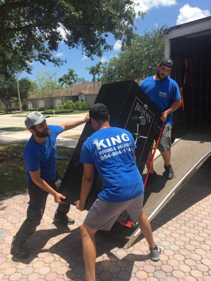 Three men moving a television set on dolly.