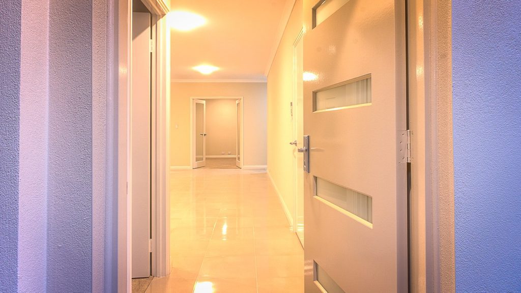 A hallway with two doors and a light on the wall.