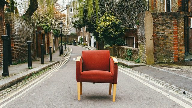 A red chair sitting in the middle of an empty street.